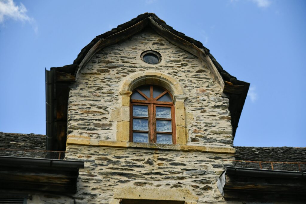 Close-up of a vintage stone building facade featuring wooden windows under a clear blue sky.